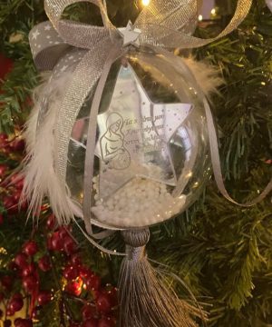 Μπάλα πλέξιγκλας με πλεξιγκλάς ασημί  αστέρι “τα πρώτα μου Χριστούγεννα στην κοιλίτσα της μαμάς ” ή κείμενο της επιλογής σας, με καρδούλα , γκρί και ασημί κορδέλες, χιόνι, φούντα ασημί μεταξωτή και φτερά λευκά